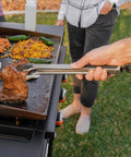 Using tongs from Professional 22 Piece Griddle And BBQ Tool Kit Stainless Steel Dishwasher Safe For Quick Cleanup