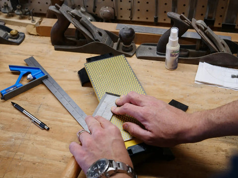 Person sharpening tool on Double Sided Diamond Sharpening Stone With Base DuoSharp 10 Inch Bench Stone Fine And Coarse For Knives And Tools