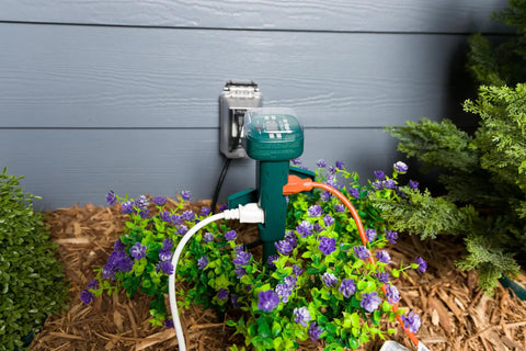 Rock Solid Outdoor Power Stake Timer With Six Grounded Outlets And Photocell Auto Switch For Yard Decor in garden with purple flowers.