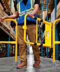 Person operating Straight Up Adjustable Spring Loaded Safety Swing Gate In High Visibility Yellow Steel on job site.