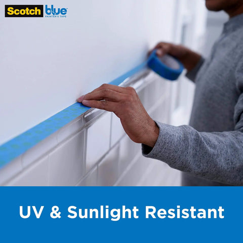 Person applying Pro Grade Sharp Lines Painter Tape on tile edge, demonstrating UV & sunlight resistance indoors.