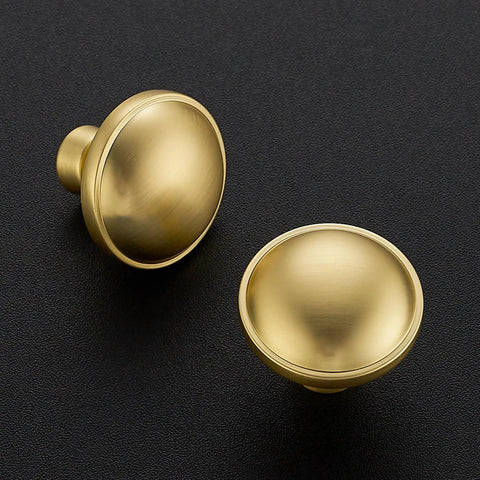 Rock Solid Zinc Alloy Cabinet Pulls Featuring A Slick Brushed Gold Finish 1 1/4 Inch Diameter Heavy Duty Kitchen Hardware Ultimate Upgrade Dreamy Cabinet Knobs 5 Pack Set Premium Corrosion Resistant Build For Long Lasting Beauty Everyday Use In Every Room. Close-up of brushed gold cabinet knobs on dark background.