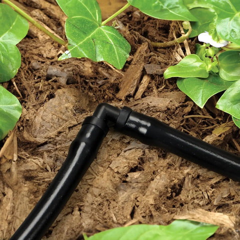 Close-up of elbow connector in 240 Piece Drip Irrigation Kit For Quarter Inch Tubing Includes Misting Nozzles Drippers Stakes Tees Elbows Plugs And More For Easy Diy Garden Irrigation System Upgrade among plants