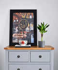 Decorative print on dresser with matte black knobs and plant next to books