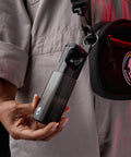 Person holding Method 360 ANC Wireless Earbuds With Bose Sound, Bluetooth Headphones in case, attached to a bag.