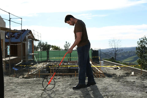 Person using 32-300RP 11 1 4 Inch Measuring Wheel With 5 Digit Ratchet Counter Rugged Beast Pro Grade Steel Frame on a construction site