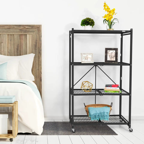 Straight Up Heavy Duty 4 Tier Foldable Steel Storage Rack In Black beside a bed, holding plants and photos.