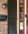 Black Wall Mount Mailbox Crafted From Die Cast Aluminum With Powder Coat mounted on brick next to a red door.