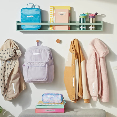 Various labeled items including jackets, backpacks, and notebooks organized using Portable Handheld Label Maker With QWERTY Keyboard And 2 Line Printing, 5 Font Sizes, 7 Print Styles, 8 Box Styles, Includes 13 Ft Black On White And Black On Clear Label Reels, Perfect For Home Organization, Crafting, And Quick Labeling.