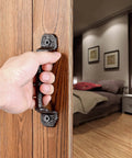 Hand using Sliding Barn Door Handles Set Of 4 In Dark Brown Cast Iron With Vintage Rustic Finish on wooden door