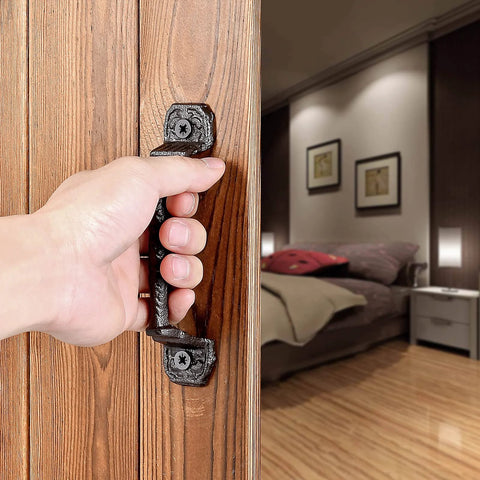 Hand using Sliding Barn Door Handles Set Of 4 In Dark Brown Cast Iron With Vintage Rustic Finish on wooden door