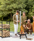 Two Tier Indoor And Outdoor Firewood Rack Portable Heavy Duty Easy To Assemble With Four Hooks To Stow Logs For Fireplaces Fire Pits And Stoves In A Sleek Black Finish shown by fire pit outdoors with people enjoying a fire.