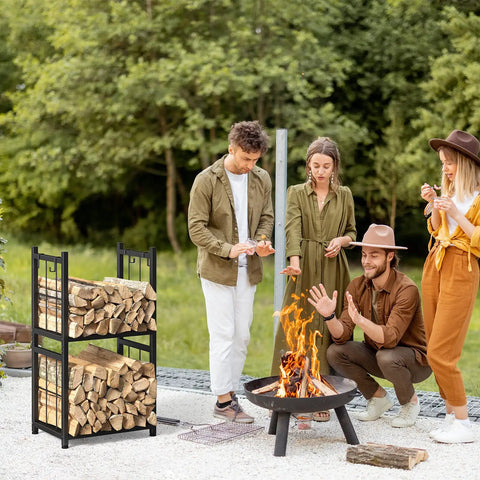 Two Tier Indoor And Outdoor Firewood Rack Portable Heavy Duty Easy To Assemble With Four Hooks To Stow Logs For Fireplaces Fire Pits And Stoves In A Sleek Black Finish shown by fire pit outdoors with people enjoying a fire.
