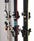 Badass Five Pack Ski Wall Hangers securely grip multiple ski boards with varying bindings in a garage setup.