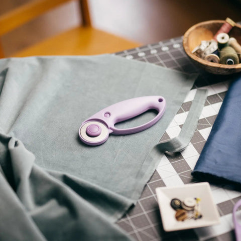 Top Tier Loop Handle Rotary Cutter For Heavy Duty Fabric And Vinyl Crafting Precision Ground Steel Blade on a sewing table with fabric.
