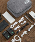 Hella Organized Travel Case For Small Electronics And Usb Charging Gear Including Phone Cables Mouse Sd Cards Power Bank Earphone Bag shown with assorted gadgets and cables on wooden surface.
