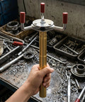 Pro Grade Smoke Sensor Extraction Tool Featuring A Rock Solid Aluminum Claw Grip, held in hand, against a workshop background.