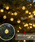 Solar String Lights Outdoor IP65 Waterproof 9.3 Feet With 20 Crystal Globe Bulbs hanging on tree during rain showing durability.