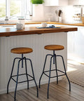 Two wooden seat barstools with black steel legs at a modern kitchen countertop, featuring Rock Solid 10 Inch Countertop Support Brackets 3 Pack.