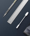 Premium Usb C To 3.5Mm Audio Adapter With Smart Dac Chip next to a ruler and stylus on a dark background.