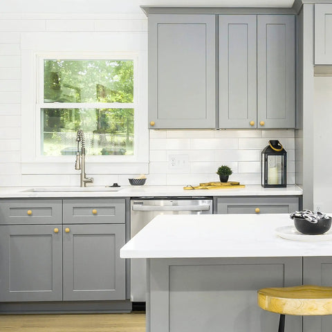 Level Up Your Kitchen Setup With This 25 Pack Of Heavy Duty Brushed Brass Cabinet Knobs Measuring 1-1/4 Inch Round Circle For A Sophisticated Vibe And Real Nice Upgrade To Any Drawer Or Vanity Project shown in a modern kitchen with gray cabinets.