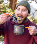 Person eating cereal with TrailSpoon Extendable Backpacking Spoon With Silicone Edge For Pots Reach Inside Cookware During Camping Trips And Dehydrated Meals Long Ten Inch Reach Three Position Locking Handle Your Go To Ultralight Utensil.