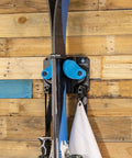 Kickin Sweet Indoor Ski And Snowboard Wall Mount With Rock Solid Damage Free Grip For Garage Storage Holds Boards Poles Safe In Space Saving Premium Gear Rack Cyan Single Pack showing skis in mount on wood wall.