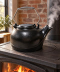 Solid Cast Iron Wood Stove Steamer And 3 Qt Humidifier Kettle with chrome handle pouring gentle steam on a wood stove.