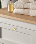 Rock Solid Zinc Alloy Cabinet Pulls Featuring A Slick Brushed Gold Finish 1 1/4 Inch Diameter on dresser with towels.