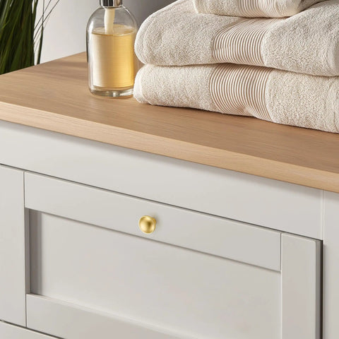 Rock Solid Zinc Alloy Cabinet Pulls Featuring A Slick Brushed Gold Finish 1 1/4 Inch Diameter on dresser with towels.