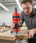 Man using 800W Palm Router Tool for woodworking compact hand trimmer with 12 piece bit set on wooden edge in workshop