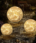 Cracked Glass Globe Solar Garden Lights Waterproof Warm White LED For Outdoor Decor glowing on pebbled pathway at night
