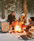 Heavy Duty Firewood Rack For Indoor Outdoor Use With Thickened Metal Construction beside family by campfire in snow