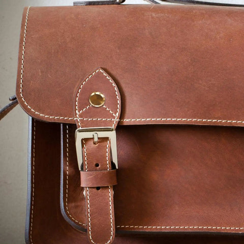 Close-up of a vintage brown leather bag with golden copper binding screws for secure closure, ideal for journal assembly.