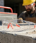 Badass Silicone Safety Glasses For Construction Work, shatterproof polycarbonate lenses resting on concrete.