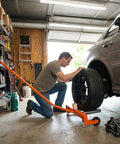 Man using Heavy Duty 660 Pound Wheel Dolly Rock Solid Tire Lifter to lift a tire in a garage workshop.