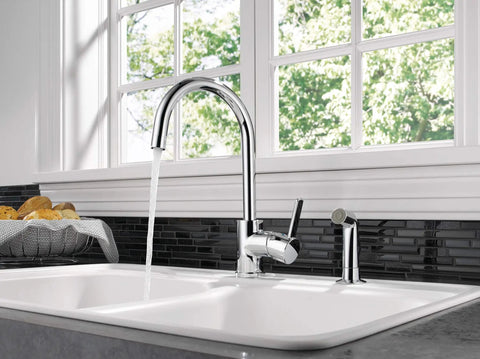 Precept Single-Handle Kitchen Faucet With Side Sprayer In Chrome, 360 Degree Swivel, installed on a dual basin kitchen sink.