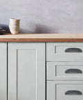Solid As A Rock 10 Pack Rustic Cup Pulls In Matte Black Iron on kitchen drawers with a wooden countertop background.