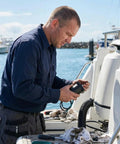 Man working on a boat holding Heavy Duty Tilt Trim Motor For Yamaha Four Stroke Outboards 12 Volt 3 Bolt Drop In Replacement for repairs.