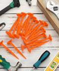 20 Pack 5 Inch Low Profile Survey Markers High Visibility Orange Yard Stakes with tools on wooden surface