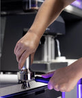Next Level Semi Automatic Espresso Machine With Built In Grinder Steam Frother, tamping coffee grounds in portafilter.