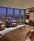 Luxury bedroom with city skyline view, modern decor, beige bedding, soft lighting, and elegant armchairs by large windows at night