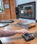 Person using iD14 MKII USB-C Audio Interface with computer in modern studio, showcasing dual headphone outputs and monitor mix.