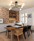 Starburst Inspired Eight Light Pendant Chandelier in Black Finish hangs in a modern kitchen with white and brick accents.