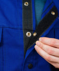 Close-up of DVALIN Hybrid FR Leather Welding Jacket with leather sleeves and snap buttons showing protective design details.