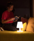 A woman reading by the Tiny Rechargeable LED Lamp 2.0 Go Anywhere Dimmable Table Light For Indoor And Outdoor Use Bright 58 Lumens.