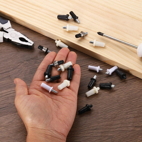 Hand holding assorted Top Shelf Spring Loaded Shutter Repair Pins 60 Piece Set Black Durable Steel fasteners on wooden surface.