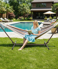 Woman reading on a 550 Lbs Capacity Hammock Stand With Portable Carrying Bag Heavy Duty Two Person Frame For Outdoors And Indoors Black Antique Finish Sturdy Steel Construction Easy Assembly All Weather Resistant