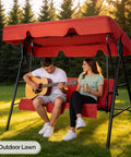 Two people sitting on Outdoor Porch Swing With Adjustable Canopy Powder Coated Steel Frame And Heavy Duty Stand For Patio Backyard Garden Or Lawn With Comfy Cushions And Weather Resistant Glider Seat In Red.