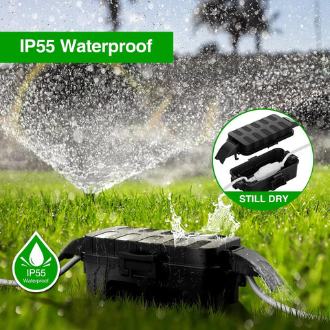 IP55 Weatherproof Outdoor Electrical Box With Detachable Awning UL Listed Compact 5.9 By 3.2 By 1.8 Inch Inner Space Extension Cord Cover For Plugs Outlets And Holiday Lights Black in grass under sprinkler showing waterproof feature.